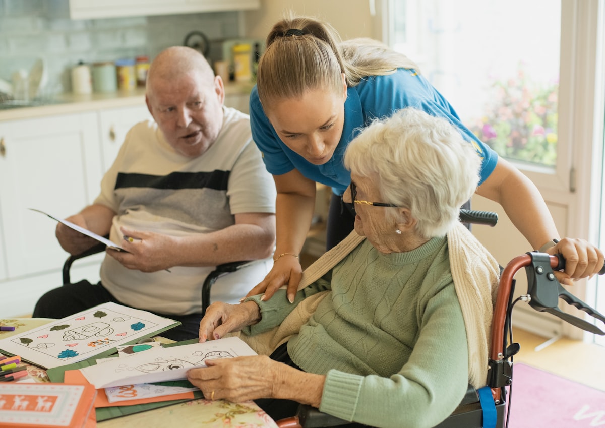 A caregiver sitting with an elderly couple during a daily check-in