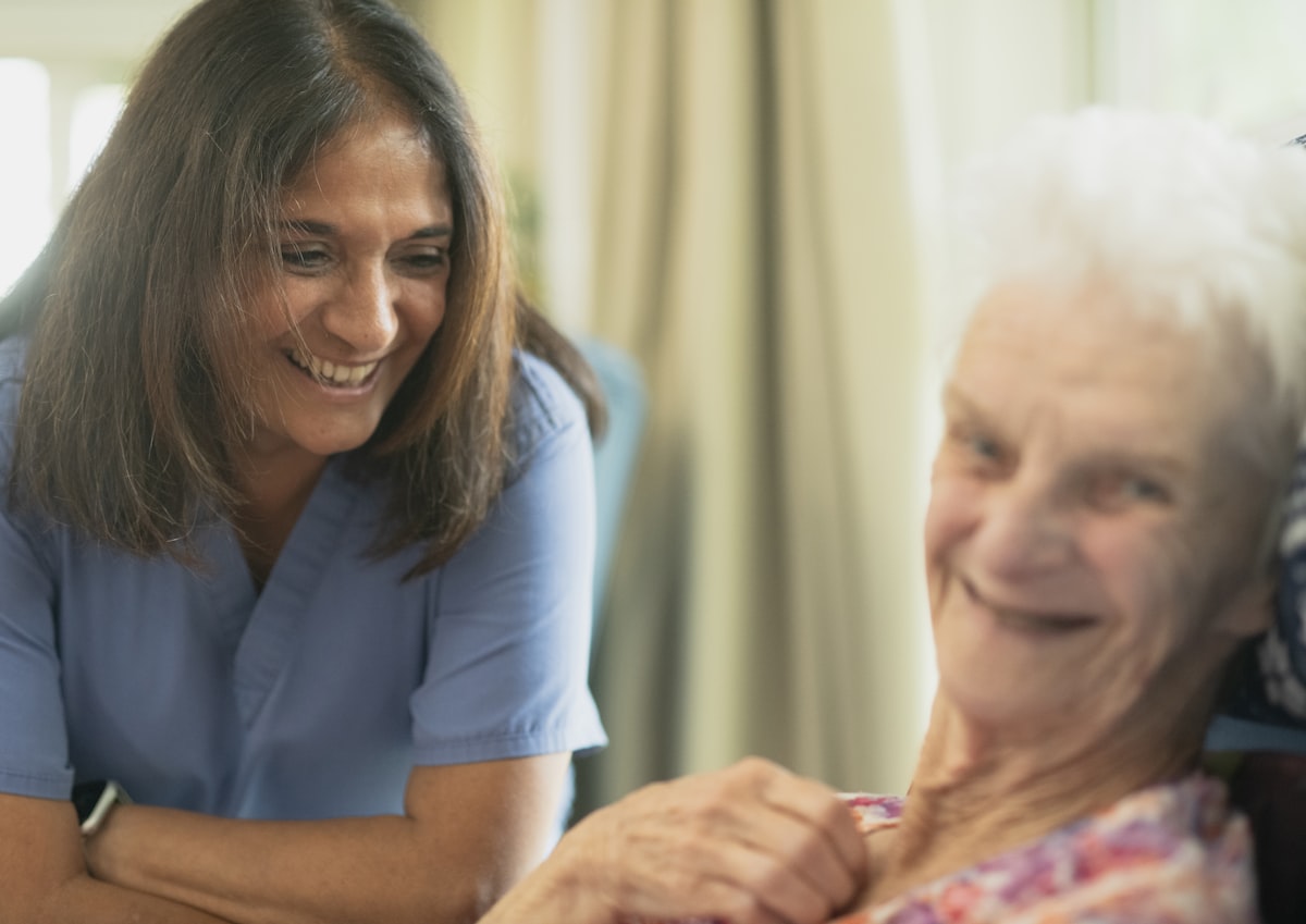 A friendly nurse smiling with an elderly patient in a bright room